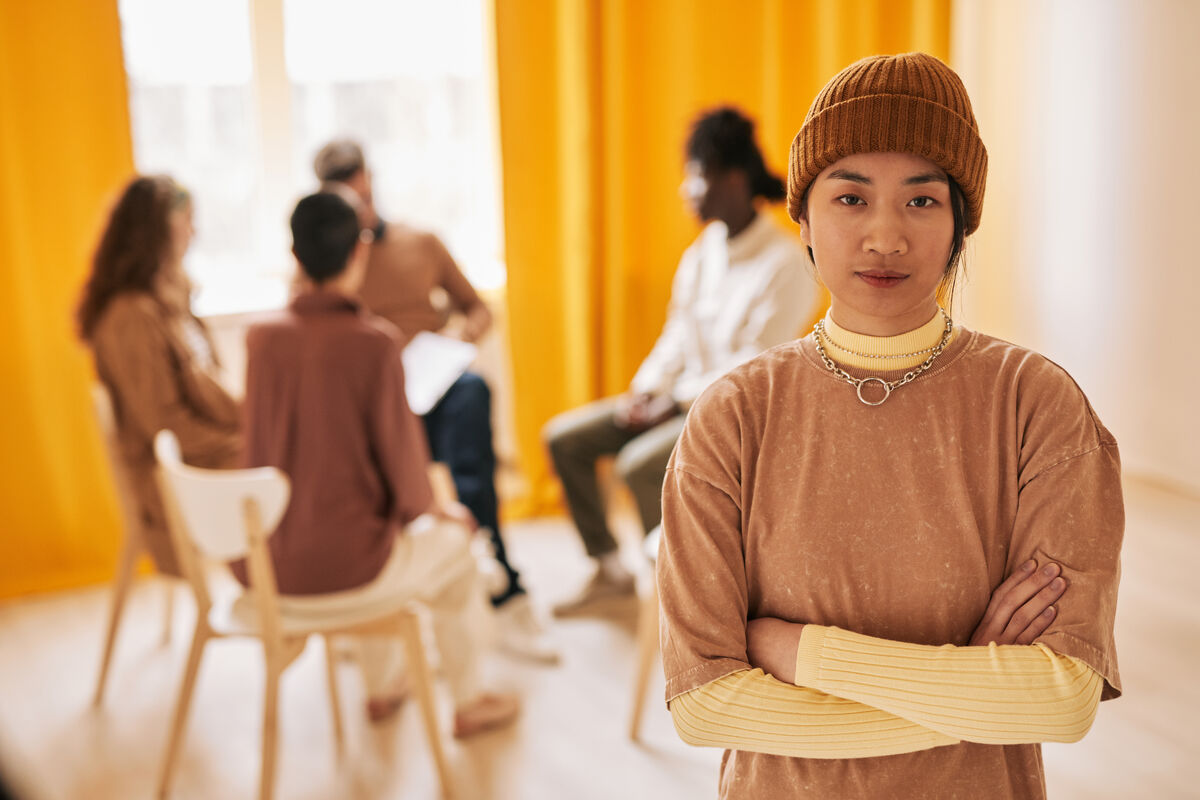 A small group of adults sitting in a circle in a warm-lit room, attentive and listening.