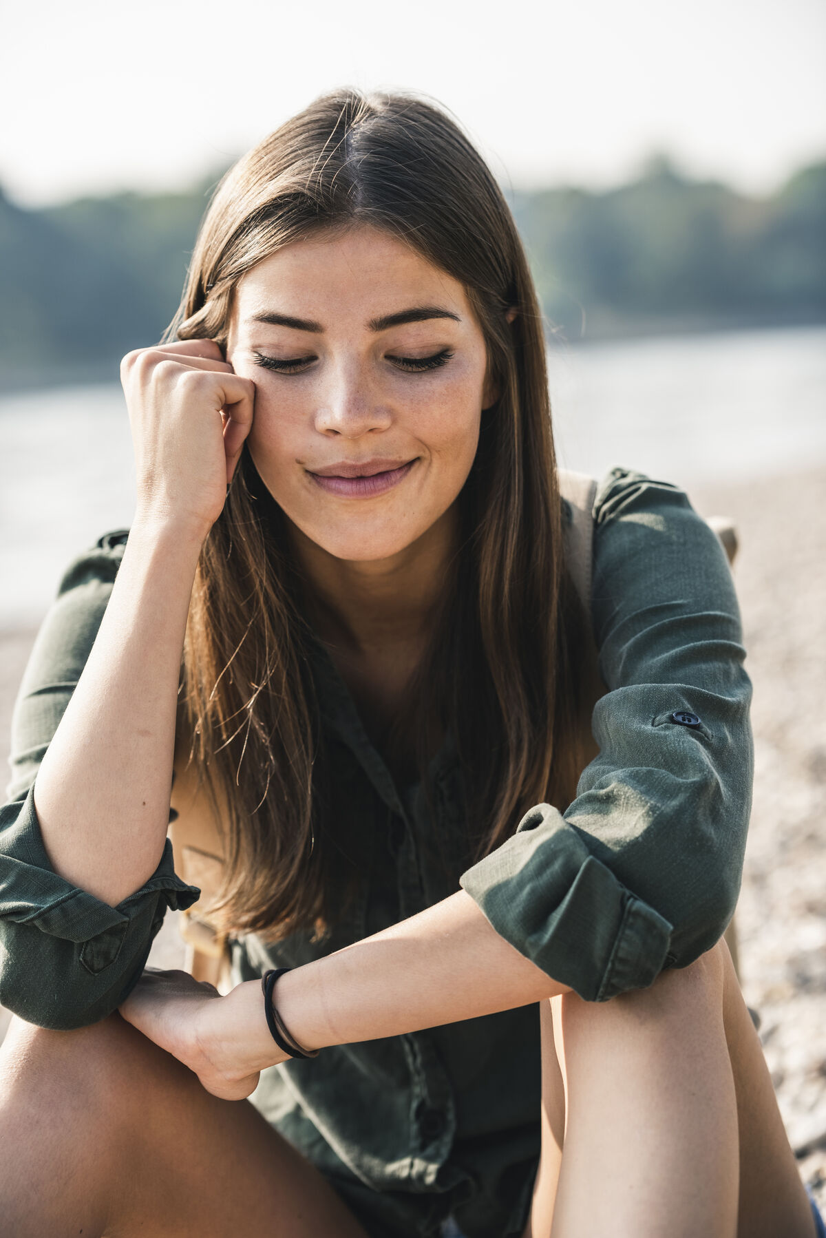 A young woman smiling outdoors in natural daylight.