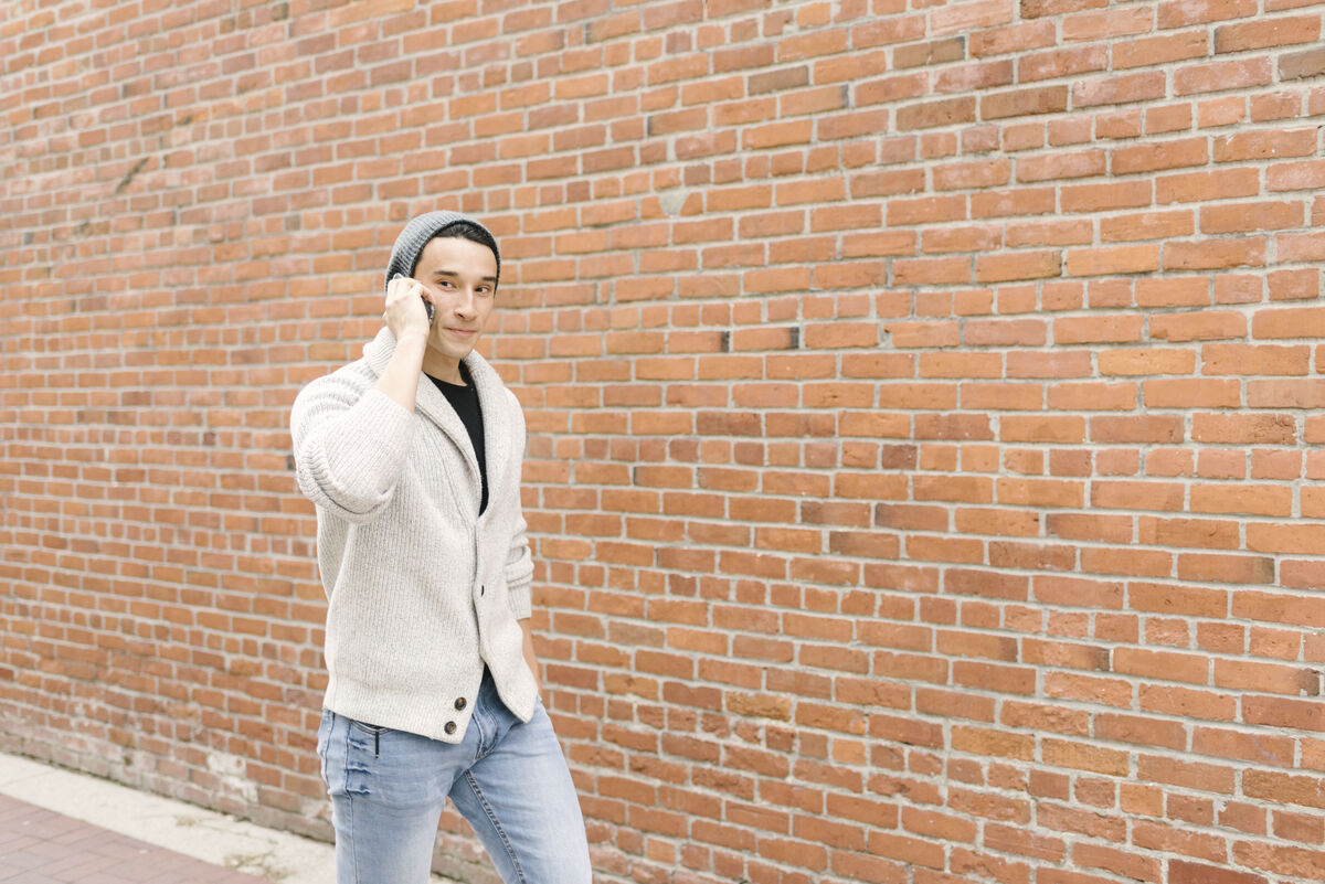 A young man on a bridge, talking on the phone, soft daylight.